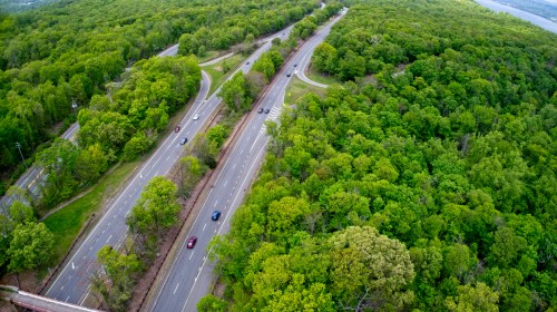 Aerial view of a winding road surrounded by lush green trees and foliage.