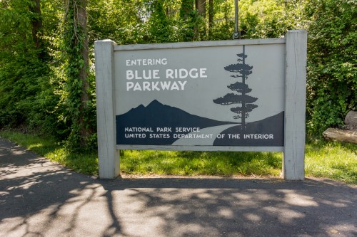 Sign for Blue Ridge Parkway, featuring mountains and trees, indicating entry to the national park.