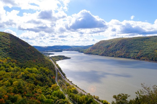 A scenic view of a river winding between green hills under a partly cloudy sky.