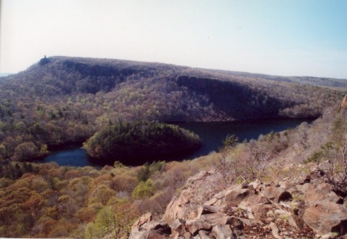 A scenic view of a river winding through lush, green hills under a clear blue sky.
