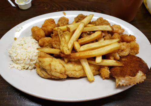 A plate of fried fish, shrimp, hushpuppies, French fries, and coleslaw.