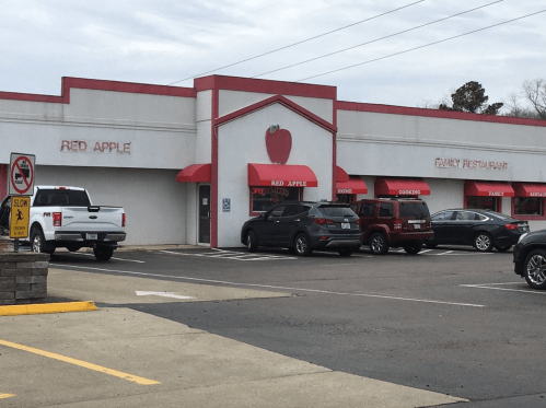 Exterior of a restaurant named "Red Apple," featuring a red apple logo and parked cars in front.