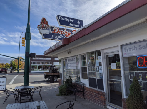 Exterior of Rodger & Jennie's Dairy Treat, featuring a sign and outdoor seating on a sunny day.
