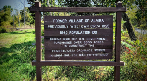 Sign marking the former village of Alvira, detailing its history and population, with information about WWII land use.