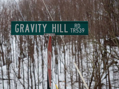 Sign for Gravity Hill Road (TR 539) with a snowy, wooded background.