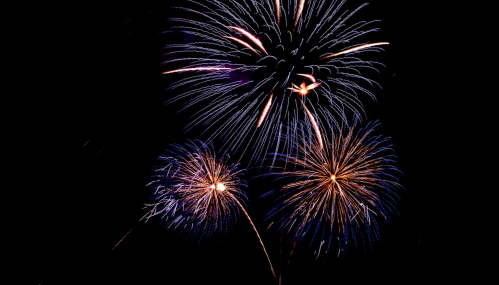 Colorful fireworks explode in the night sky, creating vibrant bursts of light in various shapes and sizes.