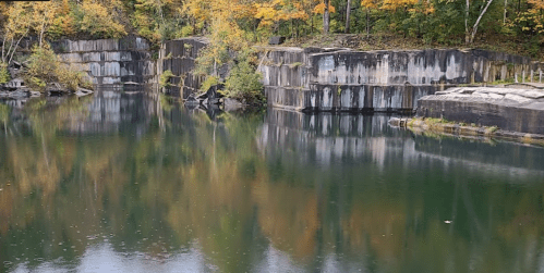 A serene lake surrounded by rocky cliffs and vibrant autumn foliage reflecting in the water.