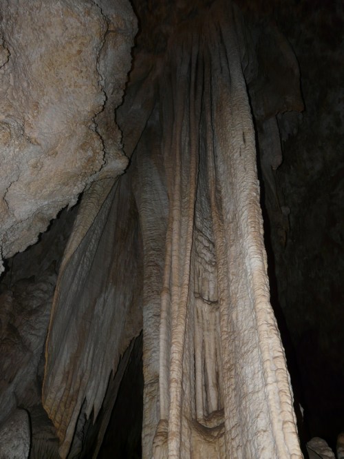 Stalactites and rock formations inside a dark cave, showcasing intricate textures and natural patterns.