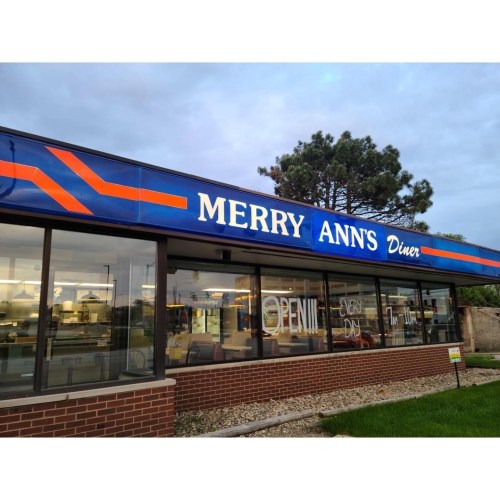 Exterior of Merry Ann's Diner with a blue sign, "OPEN" visible, and a grassy area in front.
