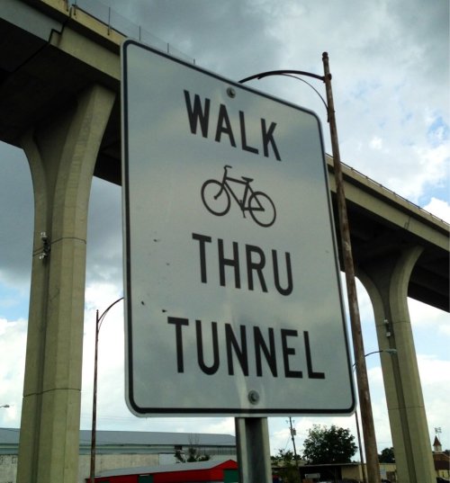 Sign indicating a bike and pedestrian tunnel, with the words "WALK THRU TUNNEL" displayed prominently.