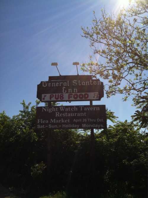 Sign for General Stanton Inn featuring "PUB FOOD" and details about Night Watch Tavern and a flea market.