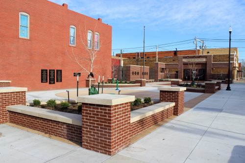 A brick plaza with benches, planters, and a clear blue sky in the background.