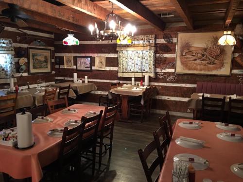 Cozy restaurant interior with wooden beams, tables set with plates, and decorative artwork on the walls.