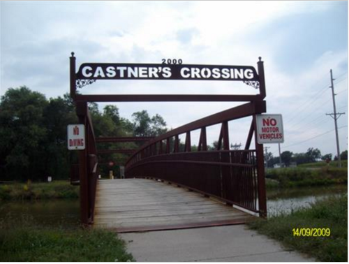 A metal bridge with a sign reading "Castner's Crossing" and no motor vehicles allowed, surrounded by greenery.