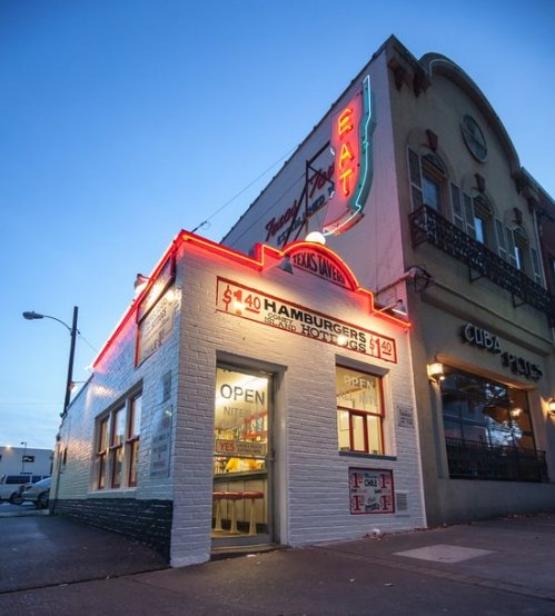 A vintage diner with neon lights, featuring a sign for $1.40 hamburgers, at dusk.