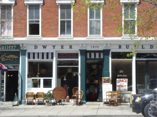 A storefront with "Dwyer Building" sign, featuring chairs outside and a "Space for Rent" sign in the window.