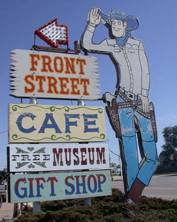 A colorful sign featuring a cowboy figure, directing to Front Street Cafe, Free Museum, and Gift Shop.
