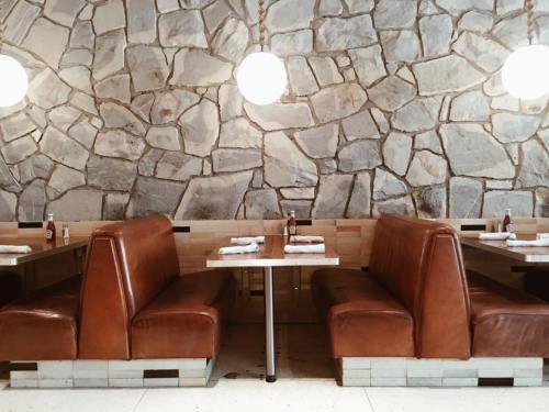 Cozy restaurant interior with stone wall, brown leather booths, and round pendant lights.