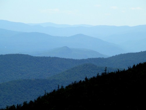 A serene landscape of layered blue mountains under a clear sky, creating a tranquil and distant view.