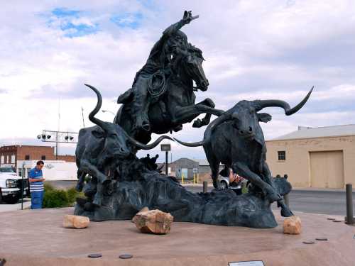 A bronze sculpture depicting a cowboy on a rearing horse, surrounded by two charging longhorns.