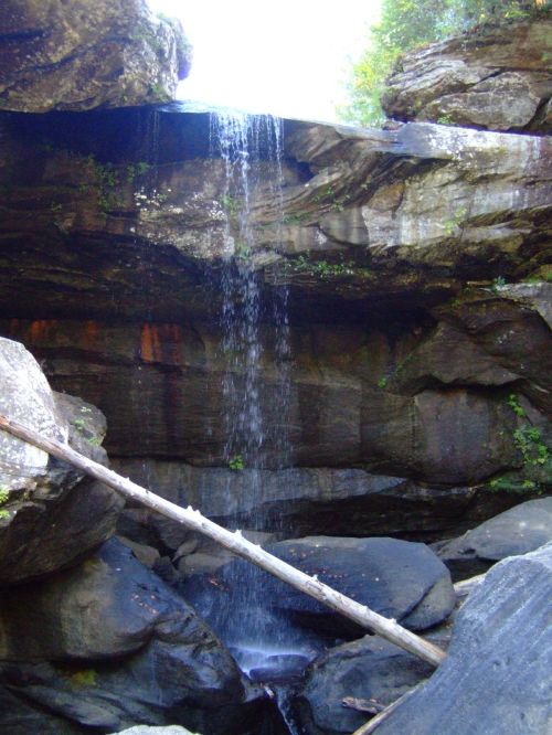 A serene waterfall cascading over rocky cliffs, surrounded by lush greenery and large boulders.