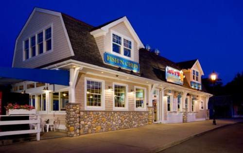 A cozy seafood restaurant with a stone facade, illuminated at night, featuring signs for "Fish 'n Chips" and "Lobster."
