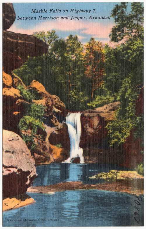 A scenic view of Marble Falls, featuring a waterfall surrounded by lush greenery and rocky cliffs in Arkansas.