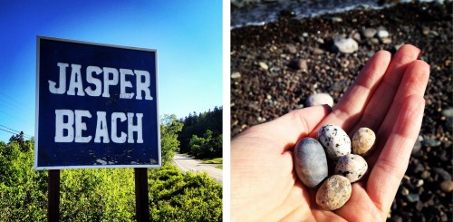 A sign reading "Jasper Beach" next to a hand holding various small, speckled stones by the water's edge.