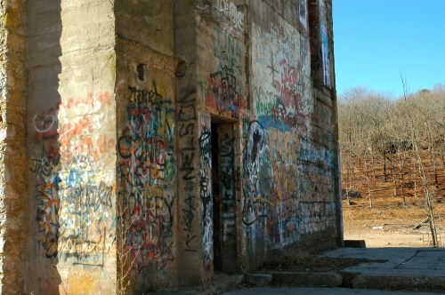 A weathered building with colorful graffiti covering its walls, set against a dry, barren landscape.