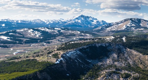 A panoramic view of snow-capped mountains and lush valleys under a clear blue sky.