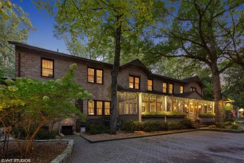 A charming brick house with a porch, surrounded by trees and soft evening lighting.