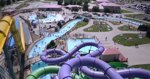 Aerial view of a water park with colorful slides, pools, and people enjoying the sun and water activities.