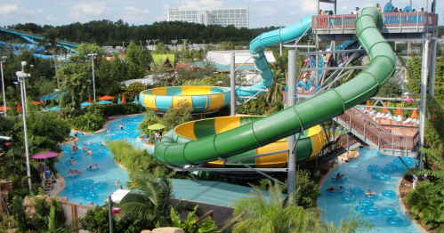 A vibrant water park scene featuring colorful slides, a lazy river, and lush greenery with people enjoying the attractions.