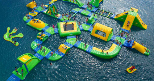 Aerial view of a colorful inflatable water park with people enjoying various activities on the water.
