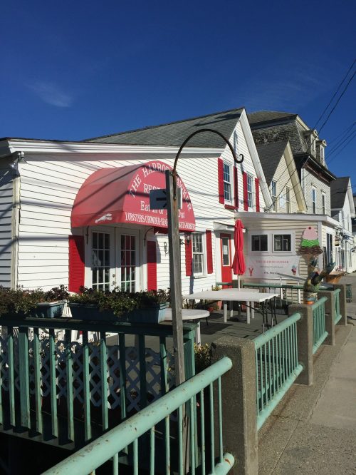 A quaint ice cream shop with red accents and outdoor seating, set against a clear blue sky.