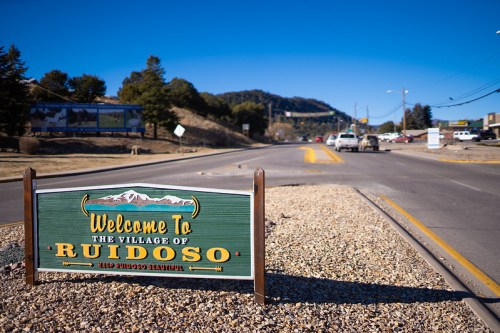 A welcome sign for the Village of Ruidoso, with mountains in the background and a clear blue sky.