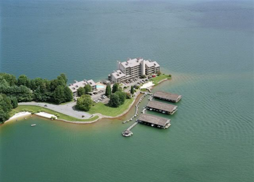 Aerial view of a lakeside resort with buildings, docks, and green trees along the water's edge.