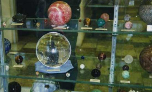 A display case filled with various decorative spheres and crystals, including a large crystal ball in the center.