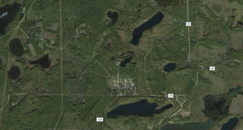 Aerial view of Trommald, Minnesota, surrounded by dense greenery and several lakes.