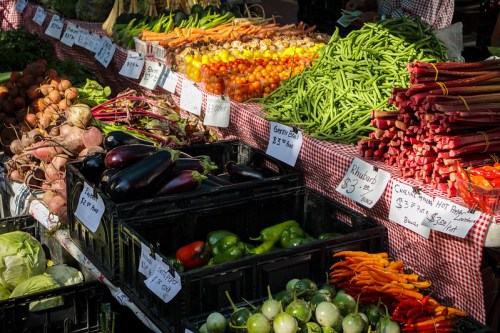 A vibrant farmers market display featuring various fresh vegetables, including tomatoes, carrots, and green beans.