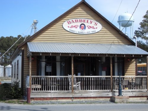 A rustic wooden building with a sign reading "Barbely's" and a water tower in the background.