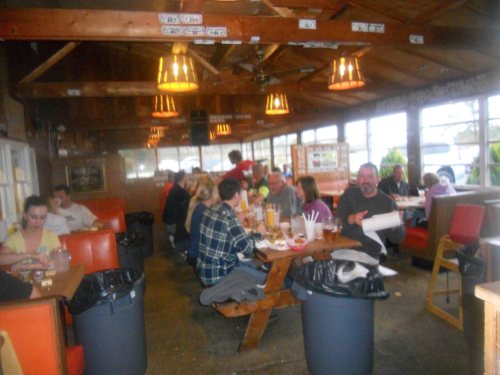 A busy restaurant interior with patrons seated at tables and booths, enjoying meals in a cozy, rustic setting.