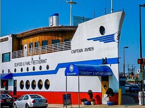 A seafood restaurant shaped like a ship, featuring a sign that reads "Captain James" and a blue awning.