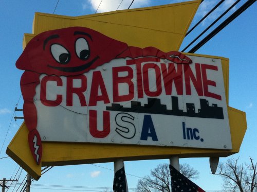 A colorful sign for "Crabtowne USA Inc." featuring a cartoon crab against a blue sky.