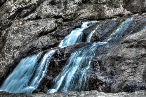 A serene waterfall cascading over rocky terrain, with clear blue water flowing smoothly.