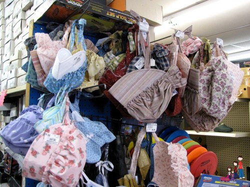 A display of colorful fabric bags and hats hanging on a blue pegboard in a store.