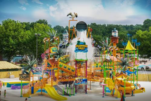 A vibrant water park featuring colorful slides, a large splash area, and playful water features under a cloudy sky.
