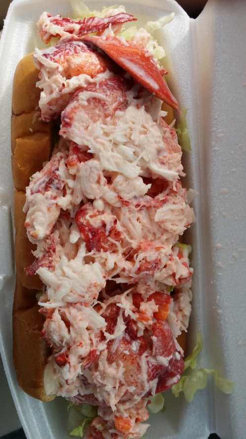 A lobster roll filled with generous portions of lobster meat, served on a soft bun with lettuce.