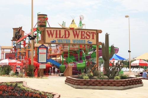 Colorful water park entrance with slides, cacti, and umbrellas, labeled "Wild West Water World."