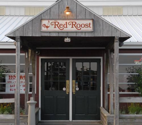 Entrance of "The Red Roost" restaurant with wooden signage and double doors under a covered porch.